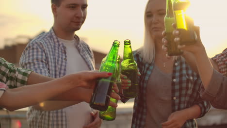 Junge-Leute-Stoßen-An-Und-Trinken-Bier-Aus-Grünen-Flaschen-Auf-Der-Party-Mit-Freunden-Auf-Dem-Dach